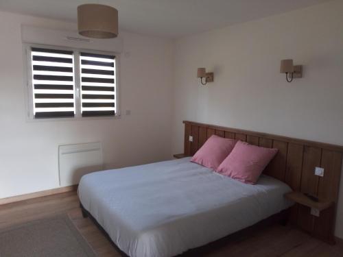 a bedroom with a bed with a pink pillow at Gîte des Garennes in Saint-Étienne-au-Mont