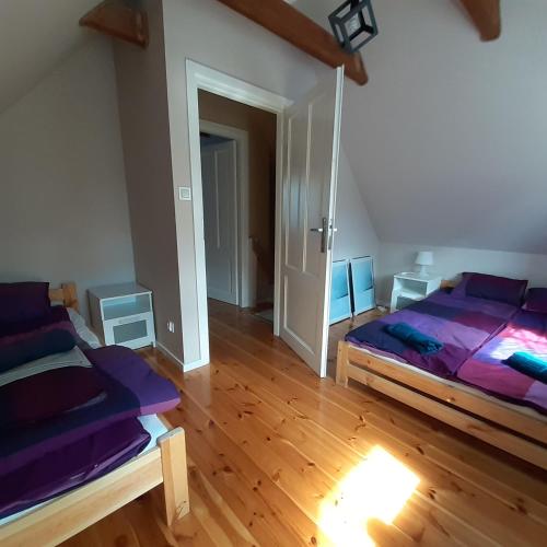 a bedroom with purple beds and a wooden floor at Letnia Ostoja Wieprz in Wieprz