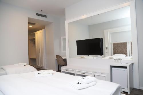 Habitación blanca con 2 camas y un espejo grande. en Sky Hotel en Prizren