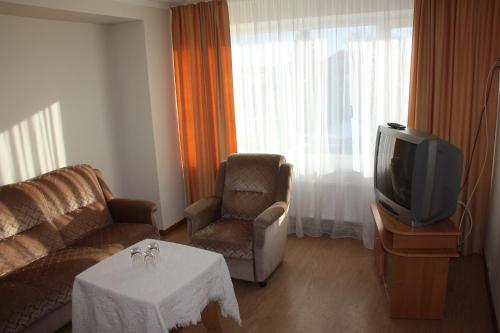 a living room with a couch and a tv at Hotel Madona in Madona