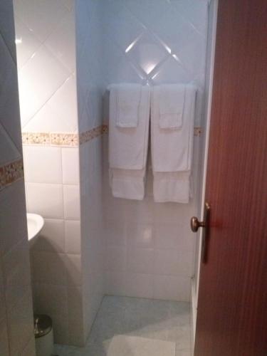 a bathroom with white towels hanging on a door at Patio das Margaridas in Óbidos