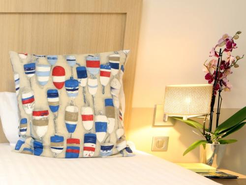 a pillow on a bed with a display of milk bottles at Trinite Hotel in La Trinité-sur-Mer
