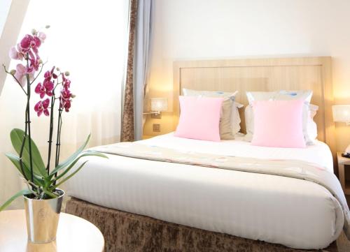 a bedroom with a large bed with pink pillows at Trinite Hotel in La Trinité-sur-Mer