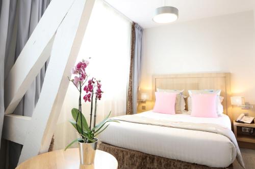 een slaapkamer met een bed met roze kussens bij Trinite Hotel in La Trinité-sur-Mer