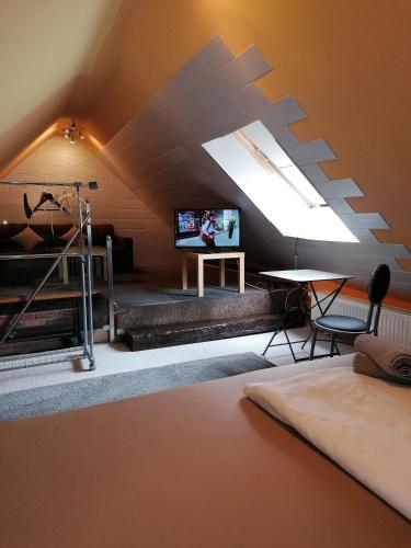 a room with a bed and a tv in a attic at Pension Riverside in Leverkusen Hitdorf am Rhein - Zentral an der A1 und 59 in Leverkusen