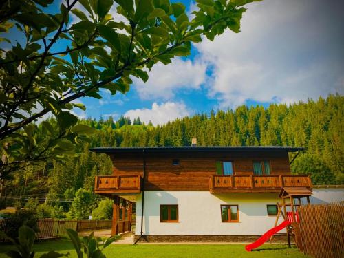a house with a red slide in front of it at Chalet Mugure de Brad in Fundu Moldovei