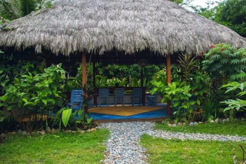 a hut with chairs and a straw roof at Cabañas Luna Escondida in Capurganá