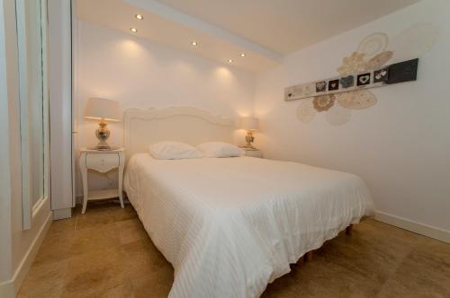 1 dormitorio blanco con 1 cama blanca y 2 lámparas en Villarama en Saint-Tropez