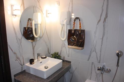 a bathroom with a sink and two bags on the wall at Hotel Cariatis in Nea Kallikrateia
