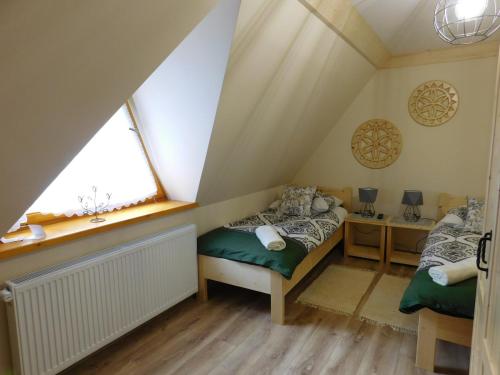 a attic bedroom with a bed and a window at Apartament w Równi in Chochołów