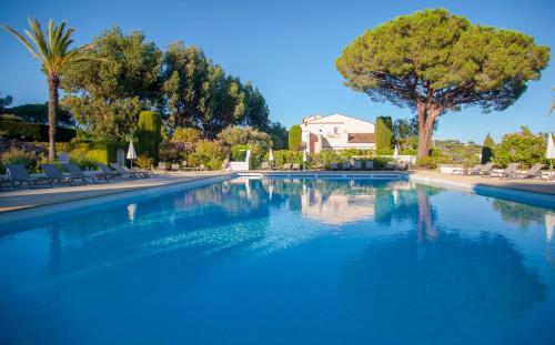 una gran piscina azul con árboles y sillas en Villarama en Saint-Tropez