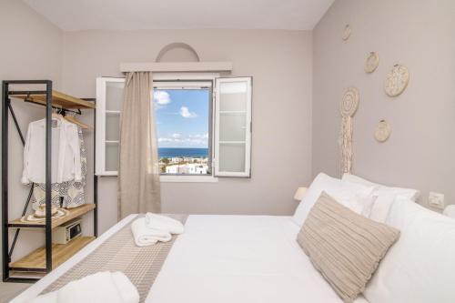 a bedroom with a white bed and a window at Porto Vidali in Agios Ioannis
