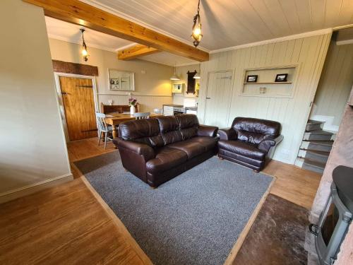 a living room with a leather couch and a table at Chapel View Cottage in Port Carlisle