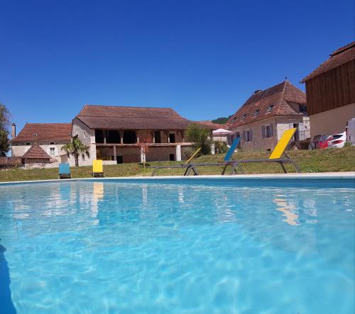 une piscine avec deux chaises et une maison dans l'établissement Gites chez Antonin, à Tour-de-Faure