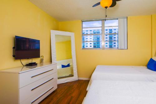 a yellow bedroom with two beds and a tv at Sunny Isles Ocean Reserve Condo Apartments - 1BR #812 in Miami Beach