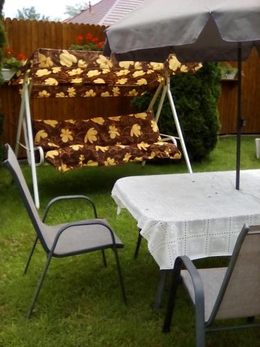 a table and chairs with a table and an umbrella at Csilla Apartman in Makó