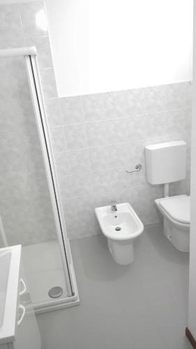 a white bathroom with a toilet and a sink at Casa Ortensia in Grions