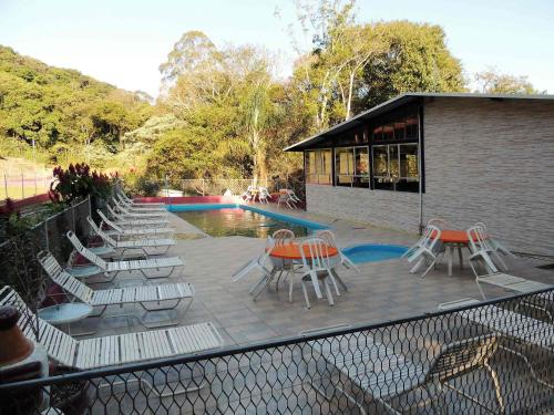 a patio with chairs and tables next to a pool at Pousada Juriti - Eco Hotel in São Roque