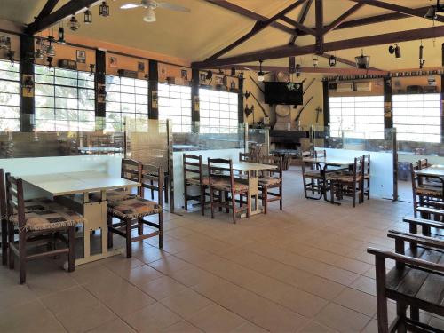 a dining room with tables and chairs and windows at Pousada Juriti - Eco Hotel in São Roque