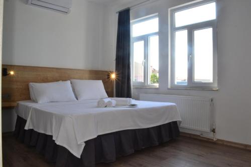a bedroom with a large white bed with windows at Parli Hotel in Gokceada Town