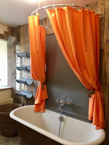une baignoire avec des rideaux orange dans une salle de bain dans l'établissement le Clos de la Livre, à Fontaine-sur-Ay