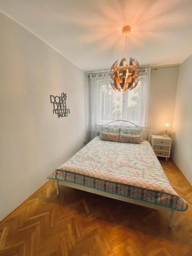 a bedroom with a bed and a chandelier at Przytulne mieszkanie na Przymorzu w Gdańsku in Gdańsk