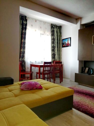 a bedroom with a yellow bed and a dining room at apartament eforie nord in Eforie Nord