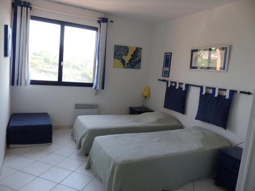 une chambre d'hôtel avec deux lits et une fenêtre dans l'établissement Soleil du Préconil, à Sainte-Maxime