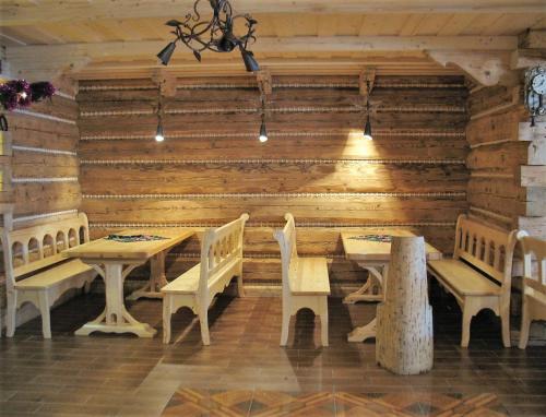 a dining room with wooden walls and tables and benches at Dom Wypoczynkowy Elżbieta in Poronin
