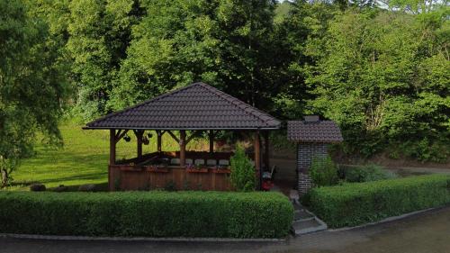 a gazebo in a garden with bushes and trees at Agroturystyka Willa Maria in Bystrzyca Kłodzka