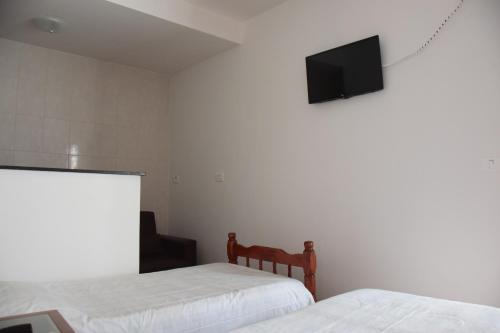 a bedroom with two beds and a television on the wall at Pousada Campos do Jordão in Campos do Jordão