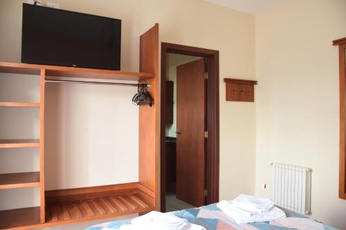 a bedroom with a flat screen tv and a mirror at Pousada Campos do Jordão in Campos do Jordão