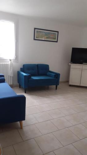 a living room with a blue couch and a television at Hôtel du Lac in Treignac