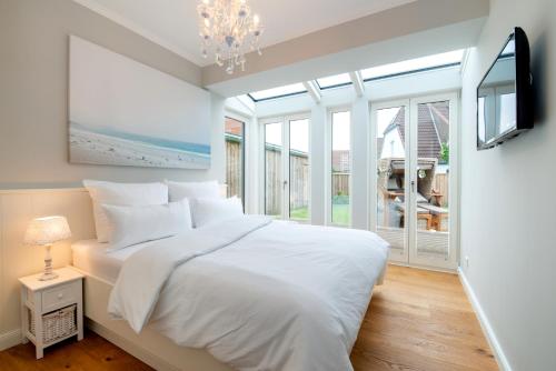 a white bedroom with a bed and a tv at KüstenHüs in Westerland