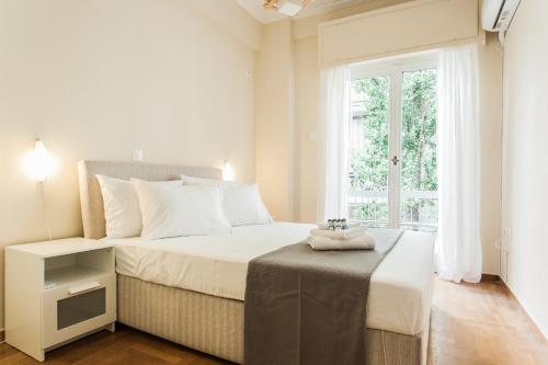 ein weißes Schlafzimmer mit einem Bett und einem Fenster in der Unterkunft La casa di Plaka in Athen