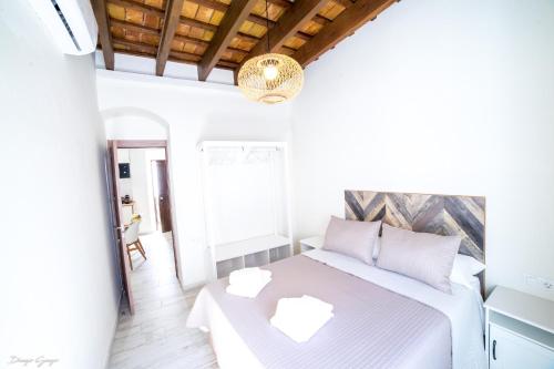 a white bedroom with a bed and a table at Apartamento Arcos in Arcos de la Frontera