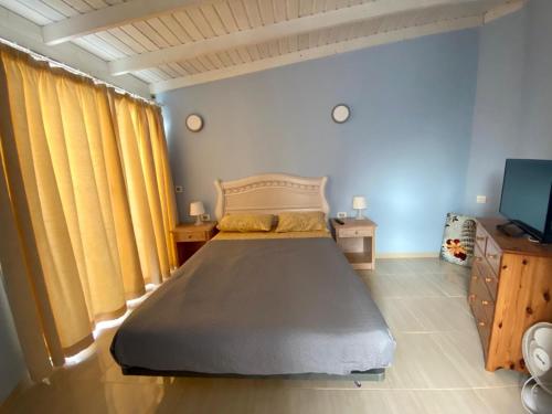 una camera da letto con un letto con tende gialle e una TV di La Tortuga ad Arona