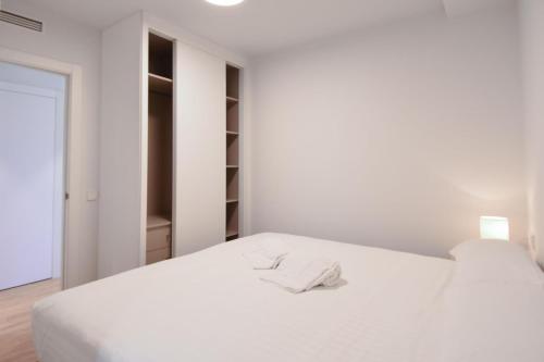 a white bedroom with a bed with a towel on it at APG Girona Carme 19 in Girona