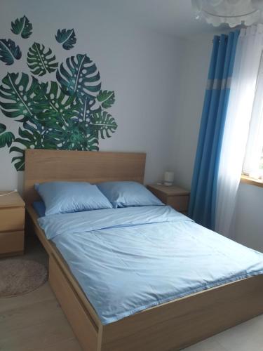 um quarto com uma cama com lençóis azuis e uma planta na parede em Apartament nr 19 em Dziwnówek