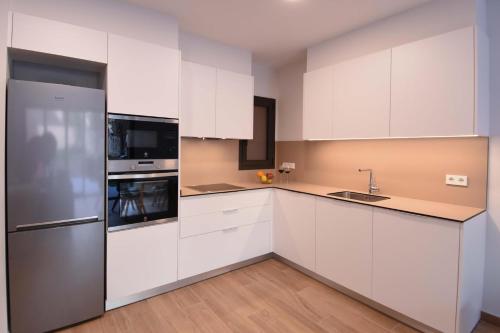 a kitchen with white cabinets and a stainless steel refrigerator at APG Girona Carme 19 in Girona