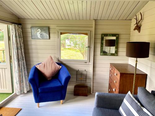 a living room with a blue chair and a window at Holly Tree Cottage - 3 bedrooms and large garden with optional glamping double outside in Lymington