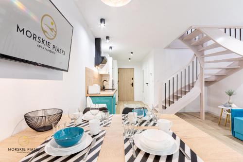 une salle à manger avec une table, des chaises et un escalier dans l'établissement Apartamenty Morskie Piaski, à Darłówko