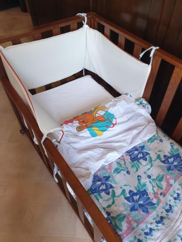 a wooden crib with a white shirt with flowers on it at Zia Zelinda in Dego