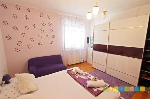 ムルテルにあるapartman klaudijoのベッド1台と紫色の椅子が備わる客室です。