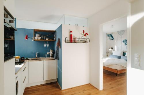eine Küche mit weißen Schränken und ein Bett in einem Zimmer in der Unterkunft Rotes Haus Bregenz See Wohnung in Bregenz
