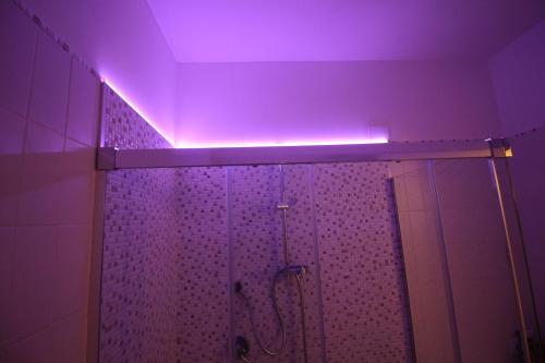 uma casa de banho com chuveiro e luz roxa em casa David em Siena