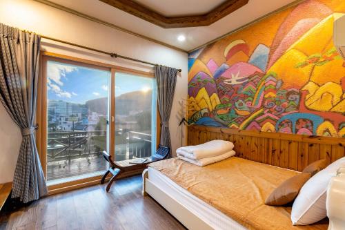 a bedroom with a large painting on the wall at Red Praha Pension in Geoje 
