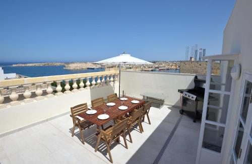 a table and chairs on a balcony with a grill at Grand Harbour Apartments in Il-Furjana