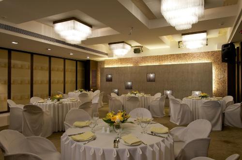 a banquet hall with white tables and white chairs at The Regenza By Tunga in Navi Mumbai