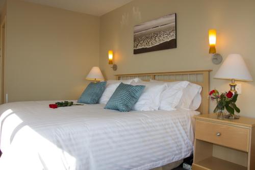 a bedroom with a large white bed with blue pillows at Rum Runner Inn in Lunenburg